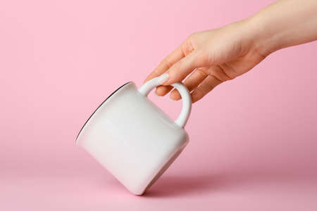 Female hand with ceramic cup on pink background, closeupの写真素材