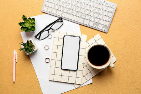 Composition with notebooks, mobile phone and cup of coffee on color background