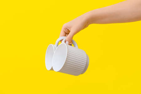 Woman holding cups on yellow background, closeupの写真素材