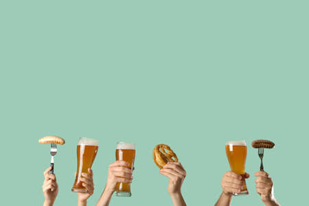Hands with beer and snacks on color backgroundの写真素材