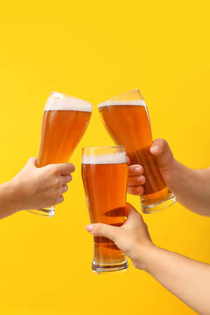 Hands with glasses of beer on color backgroundの写真素材