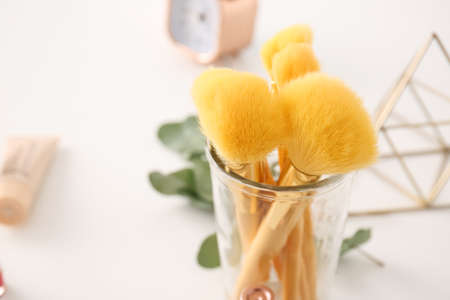 Glass with set of makeup brushes on table, closeupの写真素材