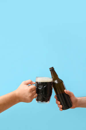 Hands with beer on color backgroundの写真素材