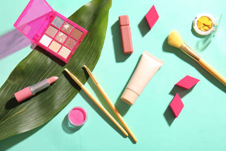 Decorative cosmetics and tropical leaves on color backgroundの写真素材