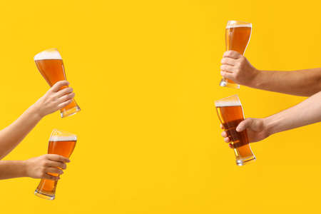 Hands with glasses of beer on color backgroundの写真素材