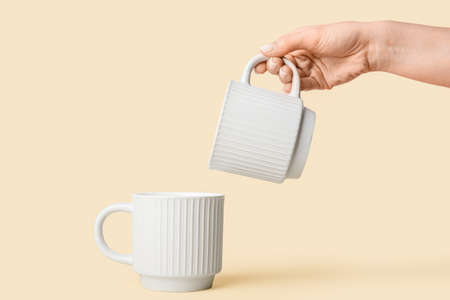 Female hand with cups on color background, closeup
