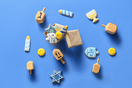 Box with tasty cookies for Hanukkah celebration and dreidels on color backgroundの写真素材