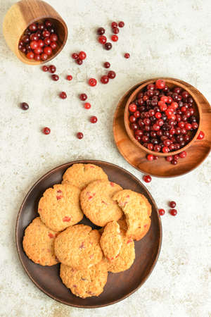 Composition with tasty cranberry cookies and berries on light background