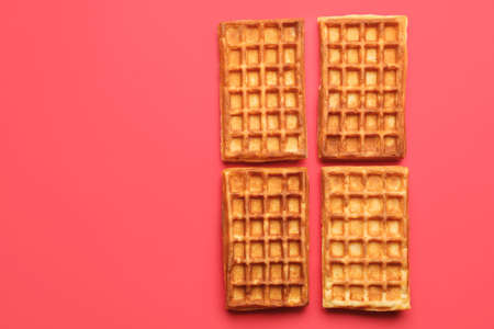 Tasty golden Belgian waffles on color backgroundの写真素材