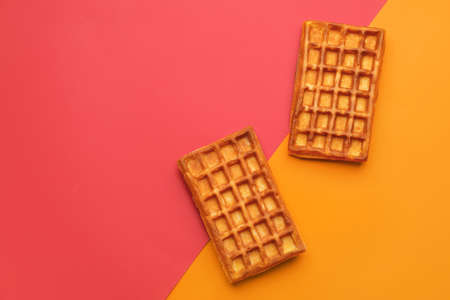 Delicious golden Belgian waffles on color backgroundの写真素材