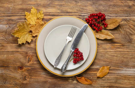 Table setting with rowan and autumn leaves on wooden backgroundの写真素材