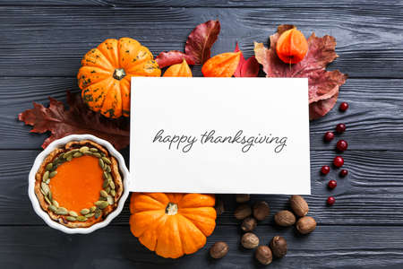 Autumn composition with pumpkins, pie and text HAPPY THANKSGIVING on dark wooden backgroundの写真素材