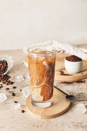 Wooden board with glass of delicious cold brew coffee and milk on grunge tableの写真素材