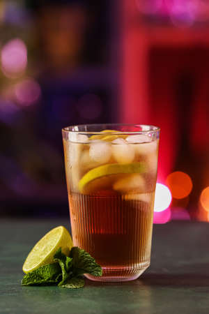 Glass of tasty Cuba Libre cocktail with lemon on table in bar