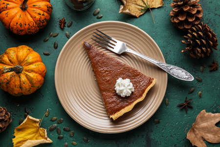 Autumn composition with piece of tasty pumpkin pie on green backgroundの写真素材