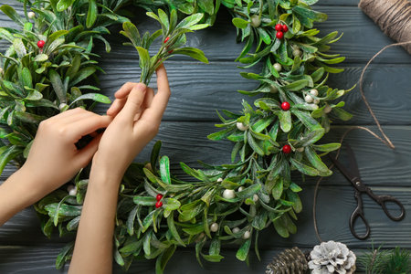 Woman beautiful decorated mistletoe wreath on dark wooden backgroundの写真素材