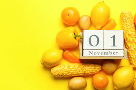 Cube calendar with date NOVEMBER 1, fresh vegetables and fruits on yellow background. World Vegan...