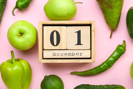 Fresh fruits, vegetables and wooden cube calendar with date NOVEMBER 1 on color background. World Vegan Day conceptの写真素材