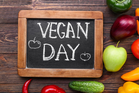 Board with text VEGAN DAY and fresh products on wooden background, closeupの写真素材