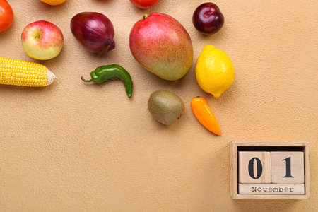 Fresh fruits, vegetables and wooden calendar with date NOVEMBER 1 on color background. World Vegan...