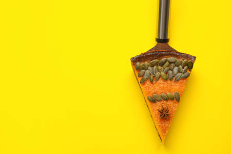Spatula with piece of delicious pumpkin pie on yellow background