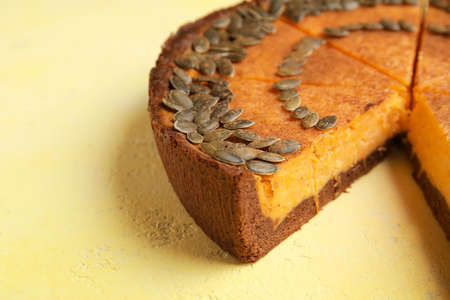 Cut pumpkin pie on yellow background, closeup