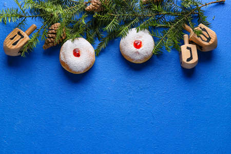 Symbols of Hanukkah with Christmas decor on color background