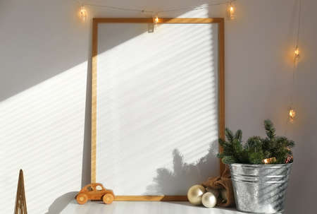 Christmas decor and blank frame on table in room