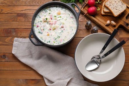 Cooking pot of tasty okroshka and ingredients on wooden backgroundの写真素材