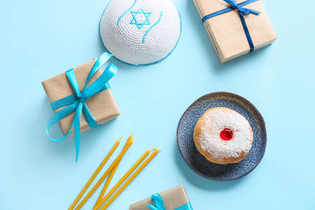 Sufganiyah for Hanukkah celebration with gifts and Jewish hat on color backgroundの写真素材