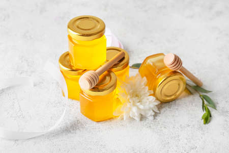 Jars with honey and dippers on light backgroundの写真素材