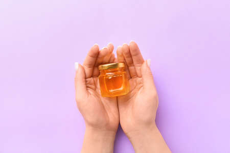 Woman holding jar with honey on purple backgroundの写真素材