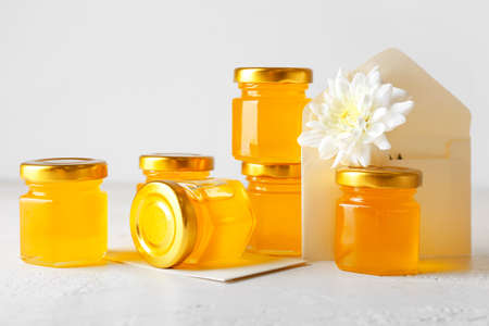 Jars with honey and chrysanthemum flower on light backgroundの写真素材