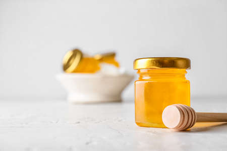 Jar with honey and dipper on white backgroundの写真素材