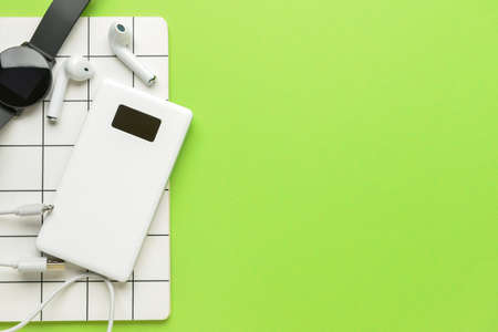 Modern power bank, earphones, notebook and smartwatch on green backgroundの写真素材