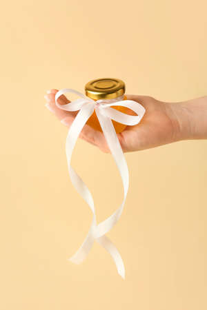 Woman holding honey bonbonniere on beige backgroundの写真素材