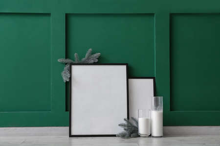 Blank photo frames, candles and Christmas tree branches near color wallの写真素材