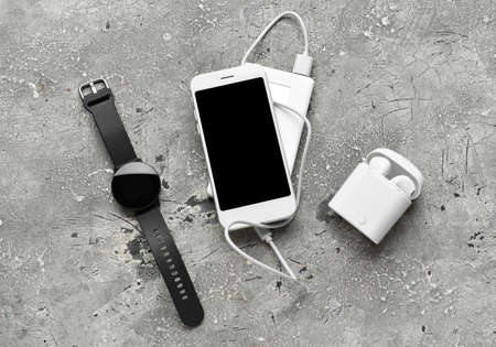 Modern power bank, smartwatch, mobile phone and earphones on grunge backgroundの写真素材