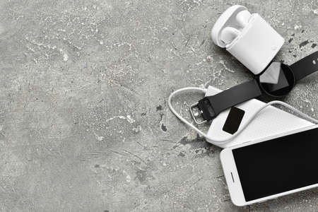 Modern power bank, smartwatch, mobile phone and earphones on grunge backgroundの写真素材