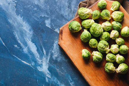 Board with fresh raw Brussels cabbage on color backgroundの写真素材