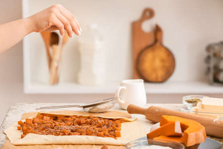 Woman cooking pumpkin strudel on table in kitchenの写真素材