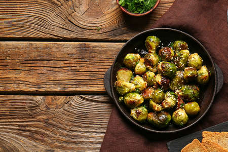 Frying pan with delicious roasted Brussels cabbage on wooden backgroundの写真素材