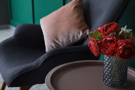 Vase with red peony flowers on coffee near armchair in room, closeupの写真素材