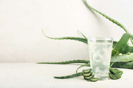 Glass of aloe juice and leaves on white backgroundの写真素材