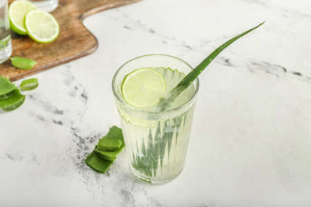 Glass of aloe juice and leaves on white backgroundの写真素材
