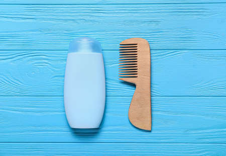 Baby hair comb and shampoo on color wooden backgroundの写真素材