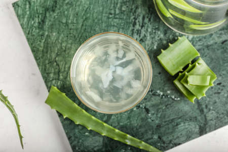 Board with glass of aloe juice and leaves on white backgroundの写真素材