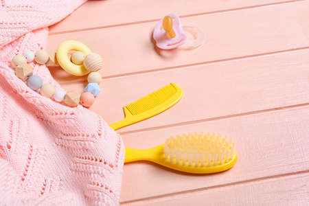 Baby accessories and knitted sweater on pink wooden background