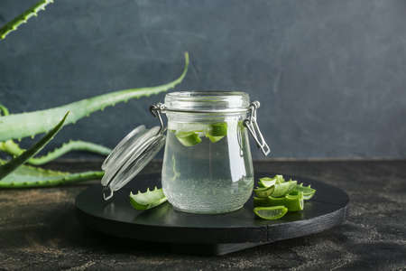 Glass jar of aloe juice with leaves on dark backgroundの写真素材