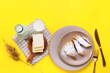 Composition with pieces of tasty pumpkin strudel and milk on yellow backgroundの写真素材